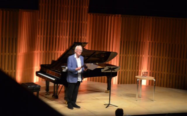 A man stood in front of a grand piano.