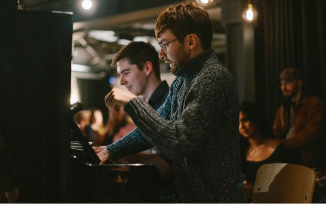 Two men at a piano.