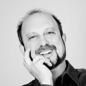 A man with a goatee resting his head on his hand.