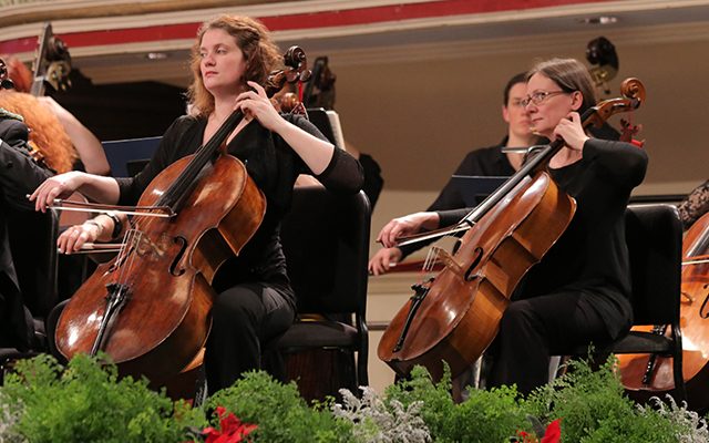 Three female cellists play in an orchestra