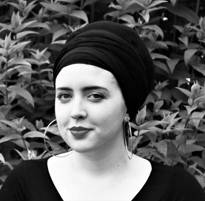 A young woman wearing large hoop earrings and a headwrap.