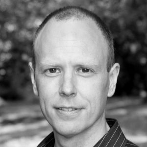 A man with short hair wearing a stripey shirt.