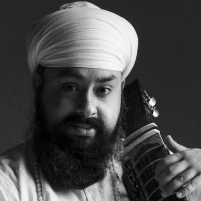 A man with a beard and wearing a turban. He is holding a Tar-Shehnai against his shoulder.