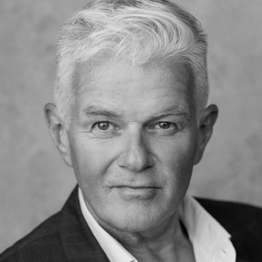 A man with short white hair wearing a suit jacket and a white shirt.